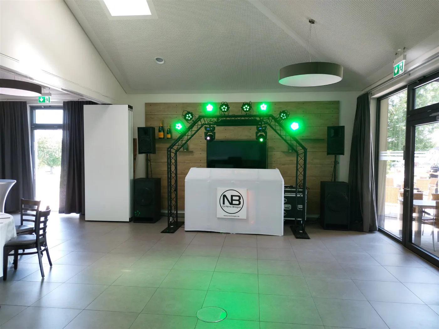 DJ-Setup im Genusswerk Karlsruhe: Traversenbogen mit grünem Licht und weißem DJ-Pult in heller Halle